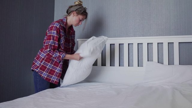 Woman cleaning her bed in bedroom, Beautiful female set up and making bed, arranging her pillows and cushions neatly
