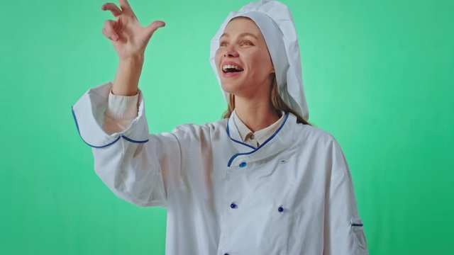 Good looking young woman baker in a green studio wall very excited with a finger working virtual ty something in front of the camera