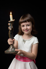 little girl holding a candlestick with burning candl