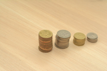 Investment/saving concept over white background. The coins are arranged in stages over wood surface