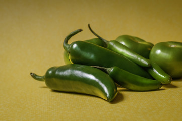 Chiles y tomates verdes sobre fondo amarillo
