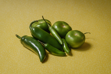 Chiles y tomates verdes sobre fondo amarillo