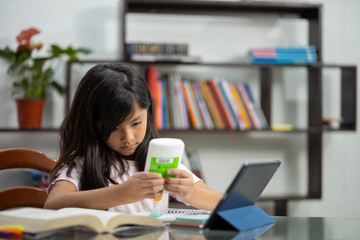 Mexican little girl pasting homework cutout, doing homework online at home due to quarantine, homeschool 