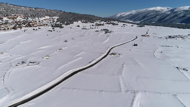 AERIAL DRONE SMOOTH FORWARD IMAGE OF COUNTRY ROAD IN SNOWED WINTER FIELDS 