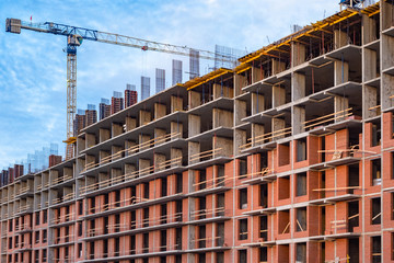 Fototapeta premium Urban construction. Multi-storey building under construction and a crane. Construction equipment. Vacancies for builders.