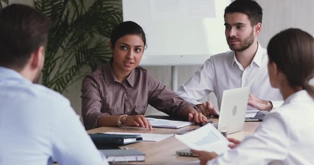 Professional young indian female marketing consultant giving advices to employees in office. Focused diverse multiracial business people discussing partnership details or developing growth strategy. - Powered by Adobe