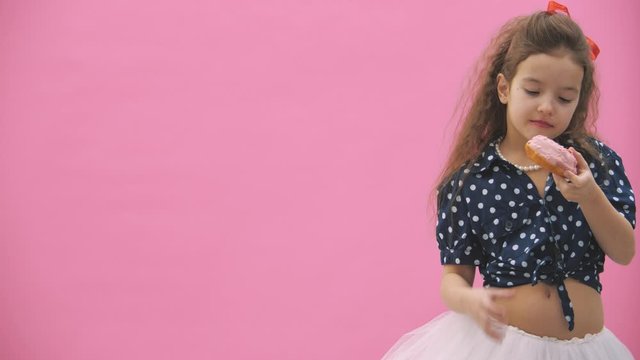 Little girl dressed in polka dot eats delicious donuts in 4k slowmotion video.
