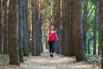 Obraz premium Young woman runner training alone outdoors in the summer forest