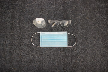 Coronavirus ( covid-19 ) prevention equipment.medical supplies. Body health care on gray asphalt. Mask, sanitizer and glasses on gray background