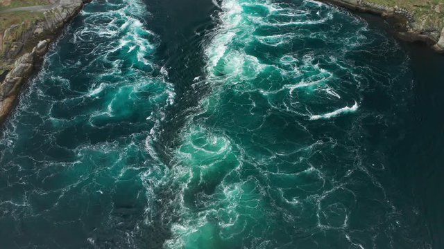 Aerial view of the famous Saltstaumen, Norway. A mass of water passing in the narrow strait. Whirlpools and eddies forming in the turquoise water, white foam rising to the surface as water rushes out.