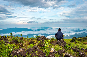 man isolated feeling the serene nature at hill top with amazing cloud layers in foreground