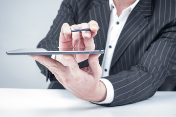 Human is showing a tablet. Man in a suit is showing something. Concept - investor shows tablet screen. Hand with gadget close-up. Businessman holds smartphone in hand. Concept - business applications