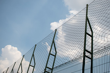 clouds over the sky behide the net fence