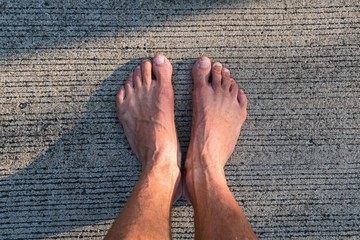 .young man stands barefoot on a warm concrete road