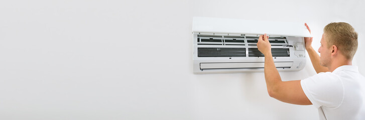 Portrait Of A Young Man Adjusting Air Conditioning System