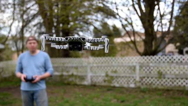 Blurry View Of A Man Standing In The Garden Outside His House While Flying A Drone  - Close up shot