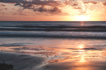 Fototapeta na wymiar Beautiful orange sunrise over the ocean in far north Queensland, white sandy beach