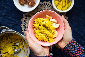 Yellow cooked millet grain cereal porridge for breakfast. Woman hands