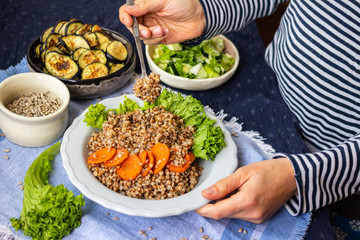 Buckwheat grain porridge - Russian traditional vegan food. Woman hands.