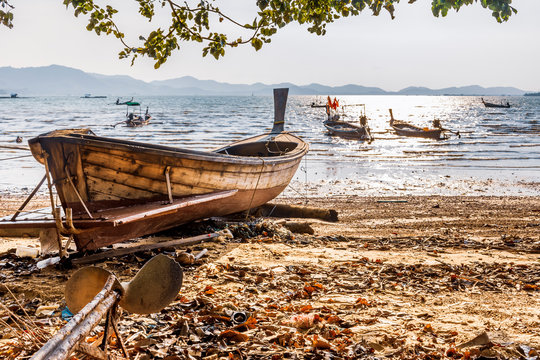 Beached & anchored long-tail boats during late afternoon windy, low tide on Ko Yao Noi island in Phang-Nga Bay near Phuket, Thailand