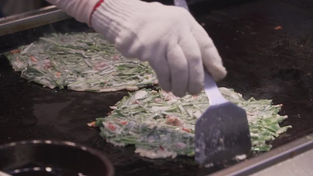 Bindae-tteok in Gukje International Market Busan city. Bindaetteok, fried buchimgae, savory pancake with ground mung beans, vegetables, meat. Korean vendors selling food in street, South Korea