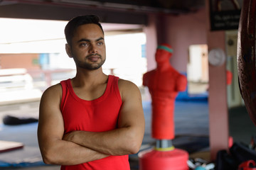 Young bearded Indian man thinking with arms crossed at the boxing gym