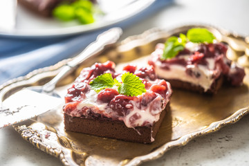 Brownie cherry cakes with cream, sour cherries and fresh mint on a vintage tray