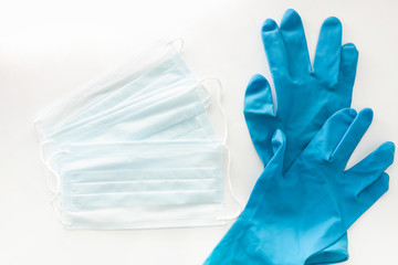 Three disposable masks for protection against viruses and blue disposable gloves on a white background top view. Minimum Outbreak Protection Kit
