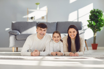 Fototapeta premium Happy smiling family hugging while lying on the floor in the room at home. C