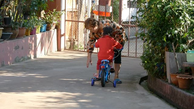 grandmother helping granddaughter ride bicycle
