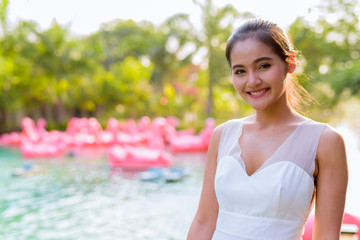 Happy young beautiful Asian woman relaxing outdoors