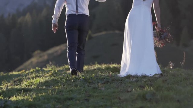Brautpaar geht gemeinsam &uuml;ber die Wiese in den Bergen &Ouml;sterreichs