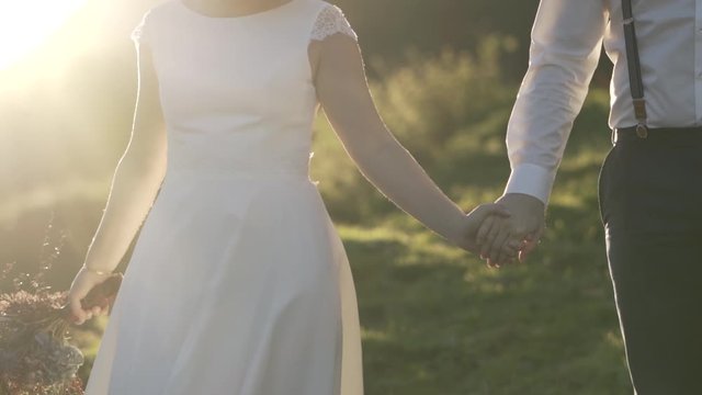 Brautpaar geht gemeinsam &uuml;ber die Wiese in den Bergen &Ouml;sterreichs