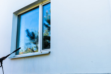 Windows cleaning with a high-pressure sprayer.  The bright blue sky is reflected in the window