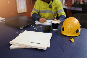 Defocused of miner setting on the chair written Job hazard analysis (JSA) with JSA templates forms on the table construction mine site Perth, Australia