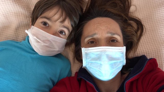 4K Covid-19 lockdown - Selfie of mother and child in medical masks looking woesome
