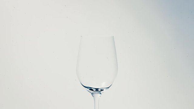 Blue paint project into wine glass in water on a white background