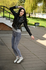 Fototapeta premium Model posing against the backdrop of a city park. Full-length portrait in sunny weather outdoors caucasian brunette girl with a great figure.