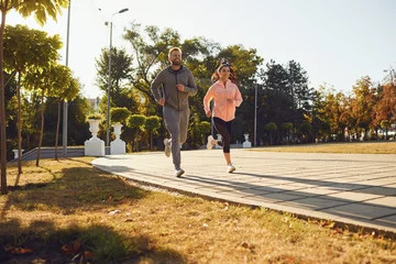 Foto op Plexiglas Sporty couple are running along the city street in the morning. © Studio Romantic