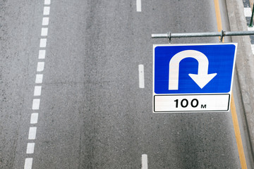 Blue u-turn sign. Sign hanging above the road.