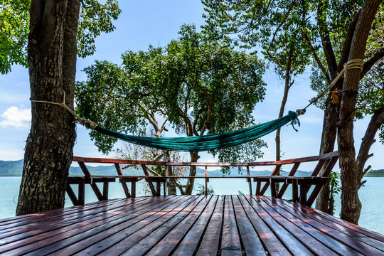 Hammock hanging between trees over wooden decking with sea view in Thailand