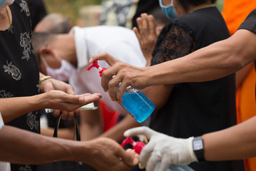 selective focus hand is holding and pressing the gel to wash the hands of other people to prevent the COVID virus.