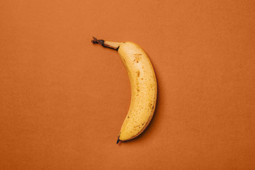 Ripe Banana With Brown Spots on orange background.
