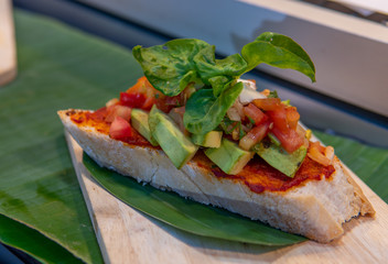 Avocado on toast served on a wooden platter with basil garnish