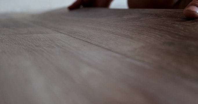 Man puts laminate on substrate, lock fastening of strips, close-up, professional at work, easy laying method, wooden boards are joined together, repair work in apartment, modern high-quality materials