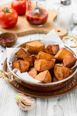 Roasted potato wedges with garlic and salt in copper pan.