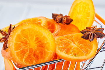 Fototapeta na wymiar Slices of dried oranges or tangerines with anise and cinnamon in a supermarket cart on a light background. Vegetarianism and healthy eating.