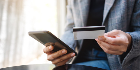 Closeup image of a woman using credit card for purchasing and shopping online on mobile phone