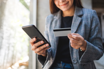 A beautiful asian woman using credit card for purchasing and shopping online on mobile phone