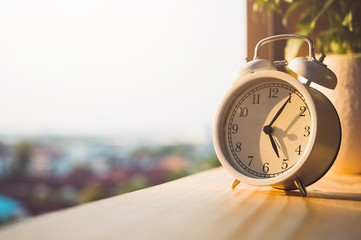Alarm Clock on wooden in the morning with sunlight.